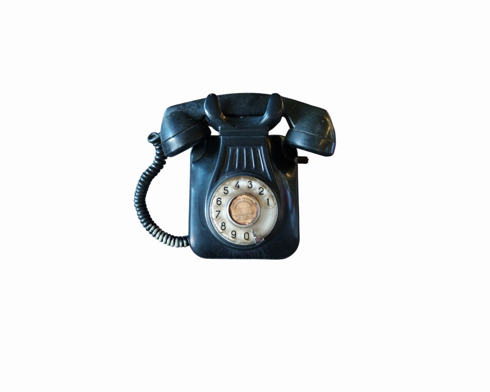 teléfono fijo de época fabricado en baquelita o plástico resistente de color negro, diseñado para su instalación mural y correspondiente a los modelos clásicos alquiler para eventos, publicidad, peliculas y series