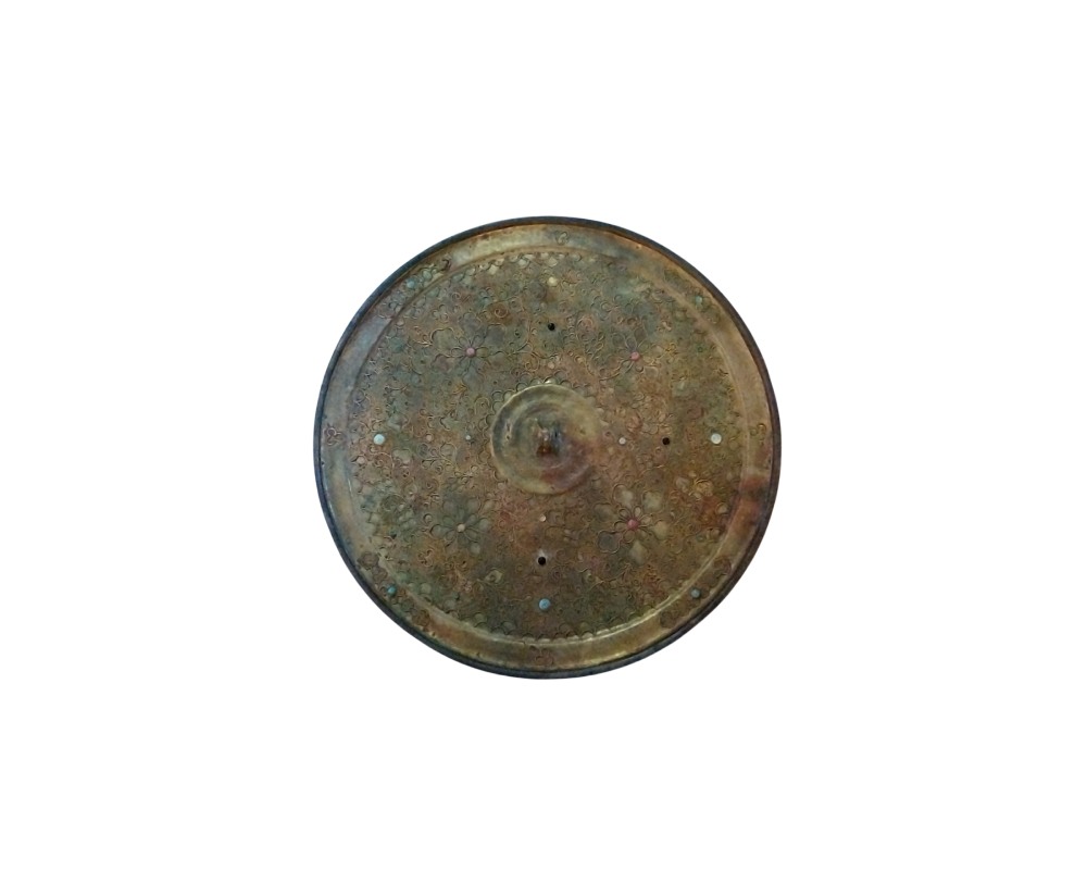 Circular metal mirror with an aged patina and a richly ornamented design on its surface; available for hire for events, advertising, films and TV series