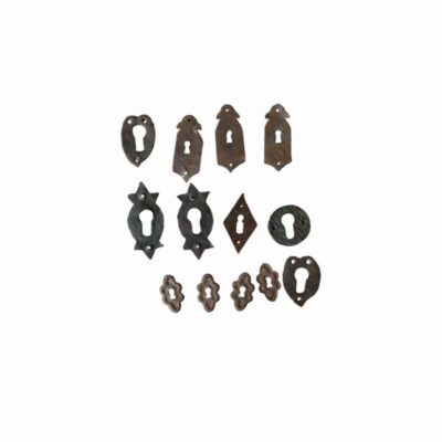lote compuesto por un variado conjunto de bocallaves o escudos de cerradura antiguos elaborados en hierro forjado, que presentan diferentes siluetas ornamentales (desde formas ovaladas y romboidales hasta perfiles lobulados y de inspiración rústica con perforaciones para tornillos) alquiler para eventos, publicidad, peliculas y series