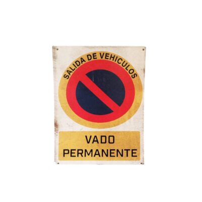 placa rectangular de formato vertical con el diseño clásico de señal de prohibición de estacionamiento, que incluye la leyenda arqueada "SALIDA DE VEHÍCULOS" en la parte superior y el recuadro inferior con el texto "VADO PERMANENTE" alquiler para eventos, publicidad, peliculas y series
