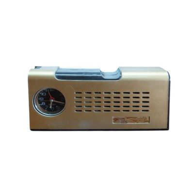 radio de época de sobremesa de diseño clásico, caracterizada por su alargada carcasa rectangular con acabado en tono dorado claro, un pequeño reloj analógico circular integrado en un lateral y una sección frontal con una distintiva rejilla de ventilación perforada alquiler para eventos, publicidad, peliculas y series
