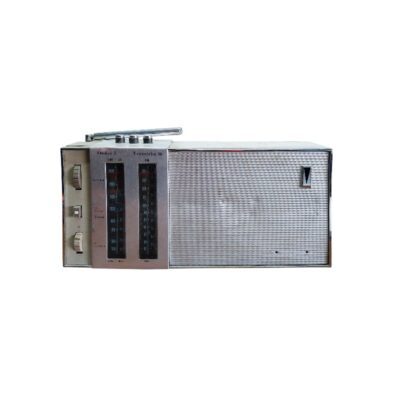 radio transistor portátil de época de diseño clásico, caracterizada por su carcasa rectangular alargada con acabado plateado, una amplia rejilla de altavoz lateral de malla metálica y un panel frontal de sintonía con diales analógicos verticales dobles y mandos de control laterales alquiler para eventos, publicidad, peliculas y series