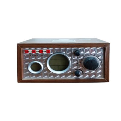 radio de sobremesa de época de diseño clásico, caracterizada por su caja exterior de madera, un panel frontal de metal plateado con relieve texturizado romboidal, una placa decorativa superior con la inscripción "Explore the World" y una sección central que integra mandos circulares y una pantalla digital redonda. Está diseñada específicamente para aportar un aspecto retro, sofisticado y de coleccionismo exclusivo a la decoración de interiores sin requerir ningún tipo de mantenimiento alquiler para eventos, publicidad, peliculas y series