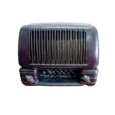 radio de mesa de la prestigiosa marca Telefunken, caracterizada por su robusto cuerpo de baquelita en tono oscuro con líneas redondeadas, una rejilla frontal con barras verticales y un panel inferior de diales con inscripciones detalladas de emisoras y frecuencias alquiler para eventos, publicidad, peliculas y series