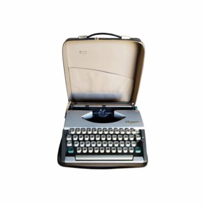 máquina de escribir portátil de diseño clásico de la marca Olympia, equipada con teclado en disposición QWERTY con eñe, cuerpo en tonos claros y su maletín de transporte rígido original con cremallera y asa alquiler para eventos, publicidad, peliculas y series