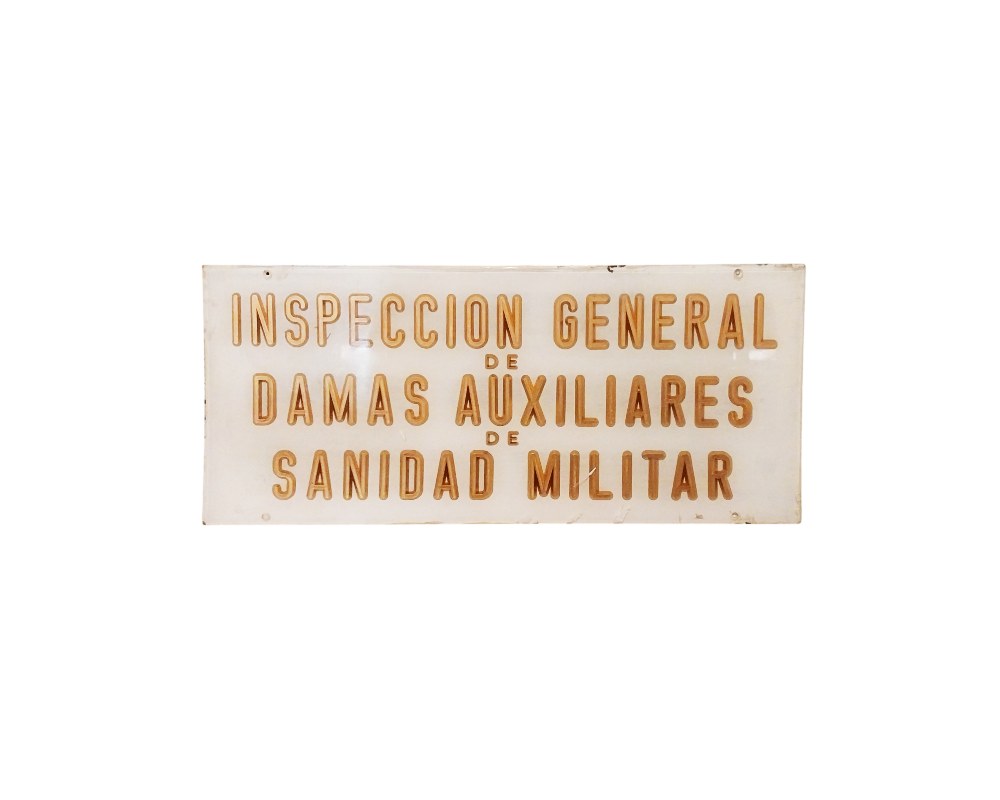 A rectangular plaque in landscape format with a light-coloured background and embossed or gold-coloured lettering bearing the official inscription ‘GENERAL INSPECTORATE OF MILITARY MEDICAL AUXILIARY LADIES’ – available for hire for events, advertising, films and TV series