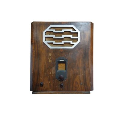 radio de época de sobremesa de diseño clásico, caracterizada por su sólida caja de madera con betas naturales visibles, una rejilla de altavoz superior de diseño geométrico metálico y un panel frontal inferior con diales y controles de sintonía integrados alquiler para eventos, publicidad, peliculas y series