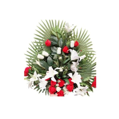 An elegant artificial floral arrangement designed around a structure of large palm leaves fanned out, combining roses in shades of red and white with delicate, highly realistic white lilies. Available for hire for events, advertising, films and TV series.