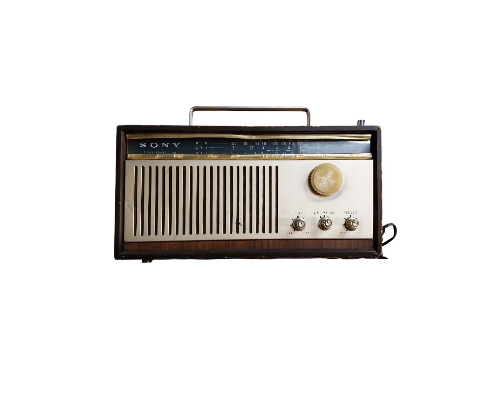 Sony portable radio, characterised by its wood-effect framed body, a metal front panel with a vertical speaker grille, rotary controls and a metal handle on top; available for hire for events, advertising, films and TV series