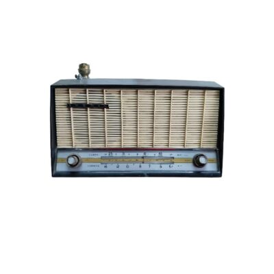 radio de época de sobremesa de la marca Iberia, caracterizada por su clásica carcasa rectangular de tonos oscuros, un amplio panel frontal con rejilla protectora de listones horizontales y una franja de sintonía inferior provista de diales analógicos y mandos circulares alquiler para eventos, publicidad, peliculas y series
