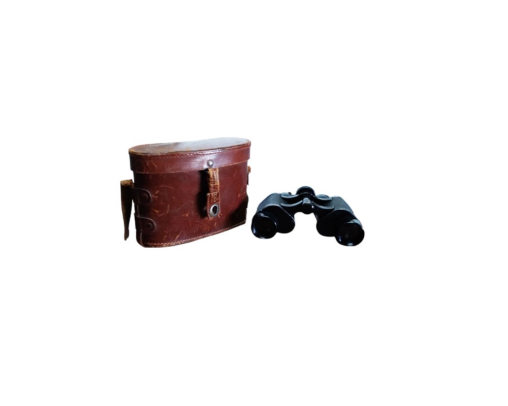 A set of classic analogue binoculars with a dark-coloured body, complete with a hard-shell carrying case in aged brown leather; available for hire for events, advertising, films and TV series