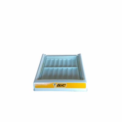 A compact tabletop display stand made from white plastic, specifically designed for displaying and organising lighters, featuring a front strip with the classic Bic brand logo in its iconic yellow frame; available for hire for events, advertising, films and TV series