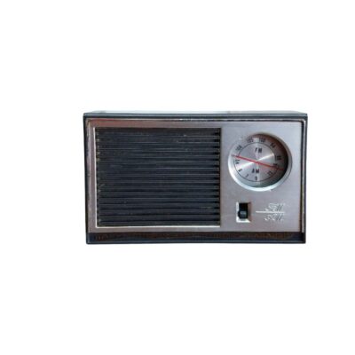 radio de época de sobremesa de diseño clásico, caracterizada por su carcasa rectangular con un panel frontal dividido en una rejilla de altavoz de listones horizontales y una sección lateral metálica plateada que integra un dial de sintonía analógico circular alquiler para eventos, publicidad, peliculas y series