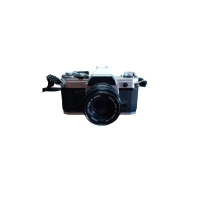 cámara fotográfica réflex analógica de época con un cuerpo metálico y revestimiento negro, correspondiente al emblemático modelo Canon AT-1, equipada con un objetivo Canon Lens FD de 50mm y una correa de transporte lateral alquiler oara eventos, publicidad, peliculas y series