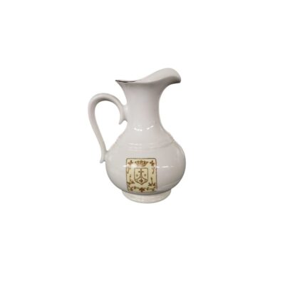 jarra decorativa de época elaborada en fina porcelana blanca, caracterizada por su silueta de base abombada, cuello estilizado con pico vertedor y un elegante escudo heráldico impreso en tonos dorados y marrones en su cuerpo central alquiler para eventos, publicidad, peliculas y series