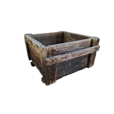 caja decorativa de época elaborado en madera maciza recuperada con una marcada pátina de envejecimiento natural, caracterizado por su formato cuadrado, tablones robustos y refuerzos estructurales perimetrales con clavos tradicionales alquiler para eventos, publicidad, peliculas y series