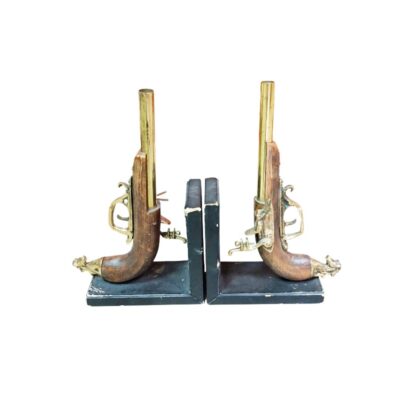 juego de sujetalibros de época caracterizado por sus soportes en ángulo oscuro y las esculturas decorativas de pistolas de chispa o duelo montadas lateralmente, elaboradas con empuñaduras de madera tallada, cañones y herrajes de latón dorado alquiler para eventos, publicidad, peliculas y series