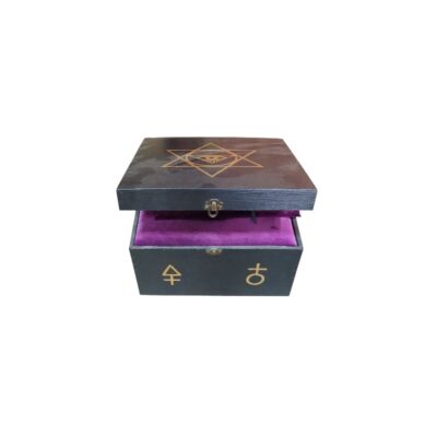 objeto decorativo de época consistente en una caja de madera oscura con símbolos alquímicos y esotéricos dorados, un interior forrado en lujoso terciopelo púrpura y una pequeña figura singular rodeada de plumas oscuras alquiler para eventos, publicidad, peliculas y series