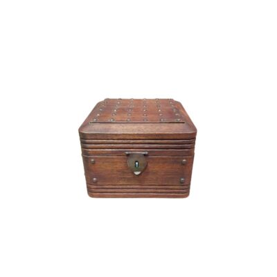 cofre de almacenamiento decorativa de época elaborado en madera noble, caracterizado por su formato compacto, molduras lineales horizontales, detalles de tachuelas metálicas en la cubierta superior y un clásico cierre de pestillo frontal alquiler para eventos, publicidad, peliculas y series
