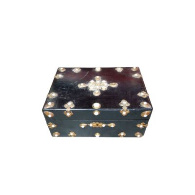 joyero de época con acabado oscuro, caracterizado por sus elaborados herrajes metálicos decorativos y llamativas incrustaciones de nácar o piedra clara dispuestas simétricamente en la tapa y los bordes alquiler para eventos, publicidad, peliculas y series